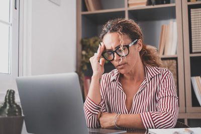 Young woman using mobile phone while sitting at home