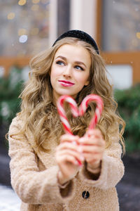 A sweet dreamy girl, a young woman holding a lollipop in the form of a heart on a winter day