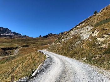 Road amidst landscape against clear blue sky