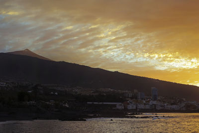 Scenic view of illuminated mountains against sky at sunset