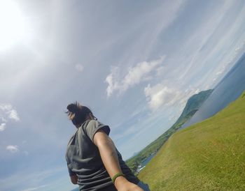 Rear view of young woman standing by sea against sky