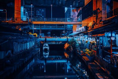 Canal amidst illuminated buildings at night