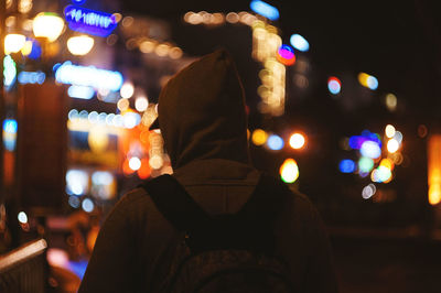 Rear view of man in illuminated city at night