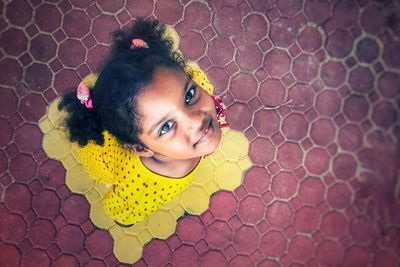 High angle portrait of smiling girl standing on paving stone