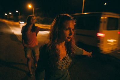 Woman looking at illuminated city street at night