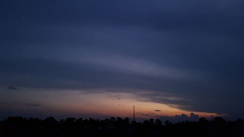 Silhouette trees against dramatic sky during sunset