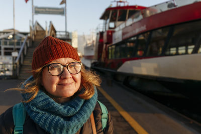 Smiling senior woman in warm clothing at harbor