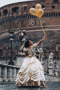 Midsection of woman with arms raised against building