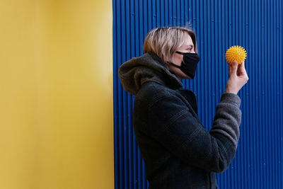 Side view of man standing against yellow wall