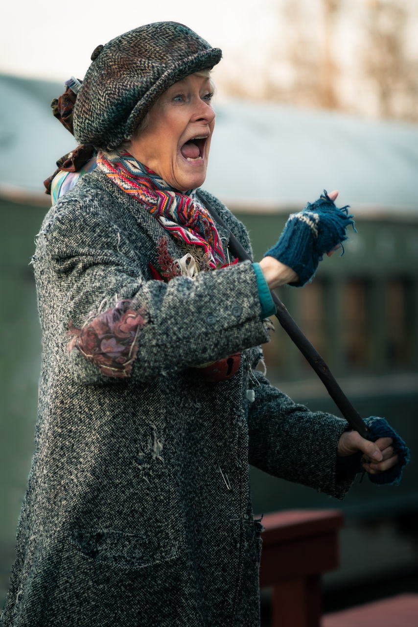 clothing, focus on foreground, one person, holding, leisure activity, real people, lifestyles, warm clothing, standing, hat, winter, knit hat, day, nature, adult, women, young adult, emotion, front view, outdoors, scarf