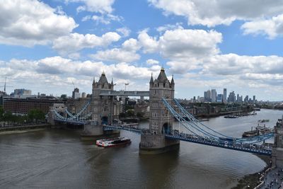 Bridge over river in city against cloudy sky