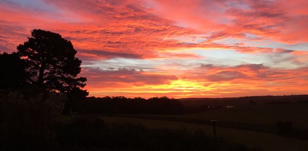 Silhouette landscape against dramatic sky during sunset