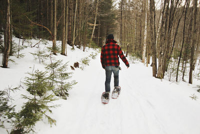 Rear view of man skating on snow covered field