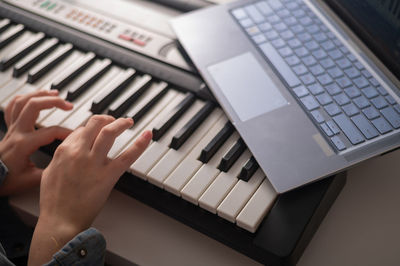 Cropped hands of woman playing piano