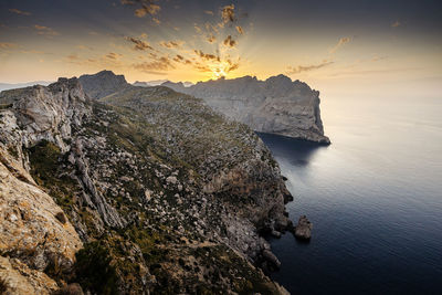 Rock formations by sea against sky during sunset