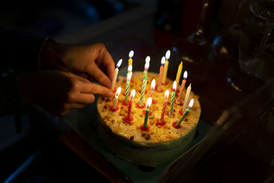 Hand placing candles on a birthday cake.