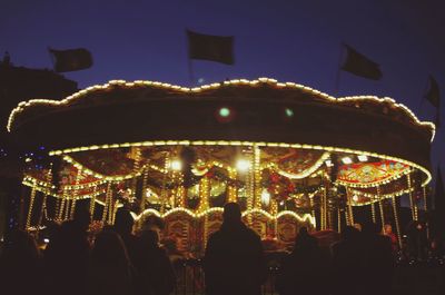 Low angle view of illuminated carousel against sky at night