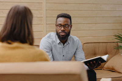 Young man wearing eyeglasses sitting on sofa at clinic