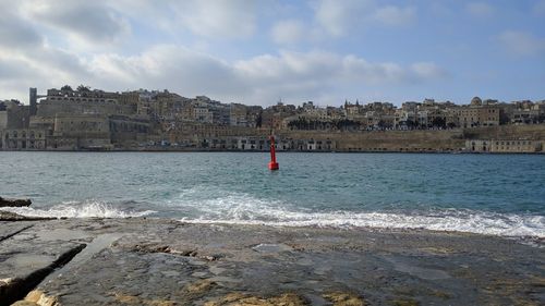 Buildings by sea against sky