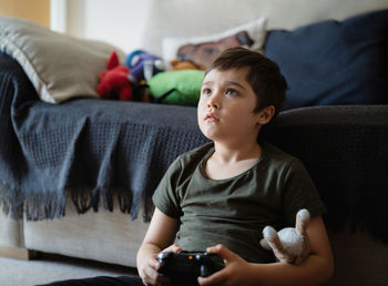 Portrait of boy using mobile phone while sitting on sofa at home