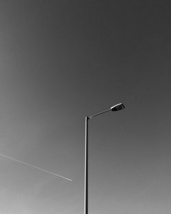 Low angle view of street light against vapor trail in clear sky