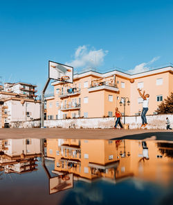 Reflection of built structure in water against blue sky