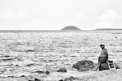 Rear view of man looking at sea against sky