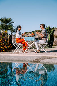 People sitting by swimming pool against sky