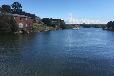 Scenic view of river by houses against sky