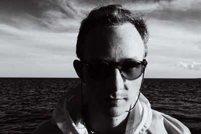 Close-up portrait of young man against sea