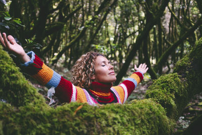 Portrait of smiling young woman standing against trees