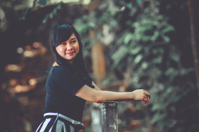 Portrait of young woman standing against trees