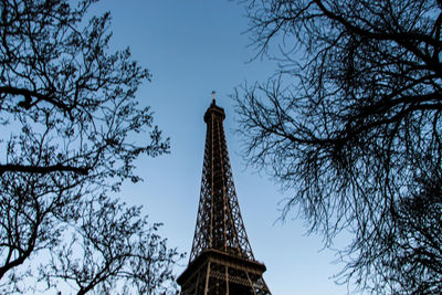 Low angle view of eiffel tower by trees against sky