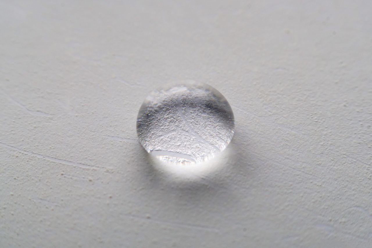 HIGH ANGLE VIEW OF GLASS ON SAND AT SHORE