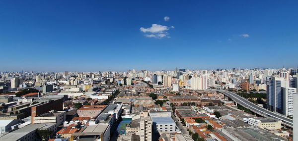 High angle view of buildings in city against blue sky