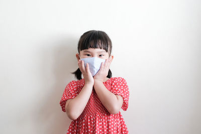 Portrait of happy girl standing against wall
