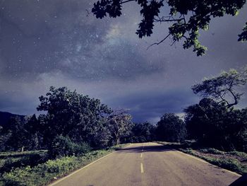 Road amidst trees against sky at night