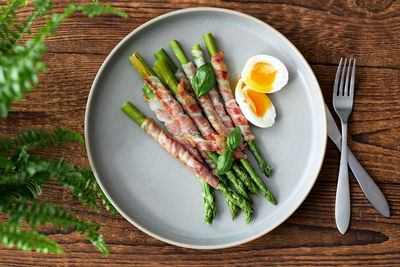 Fresh asparagus wrapped in bacon and grilled, served with egg benedict. healthy food.