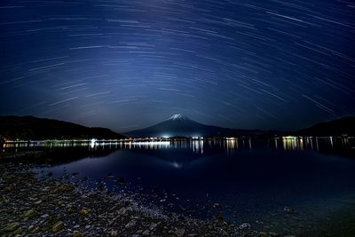 Illuminated bridge over river against sky at night