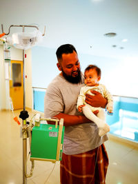 Father carrying cute daughter while standing in hospital corridor