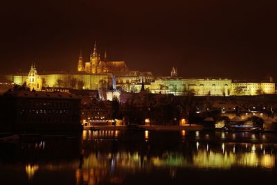 Illuminated prague castle by vltava river at night