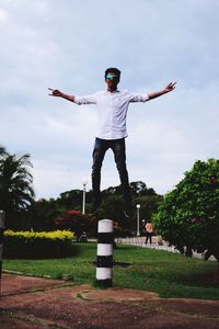 Rear view of man with arms outstretched standing against sky