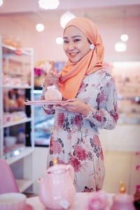 Portrait of a smiling young woman standing in store