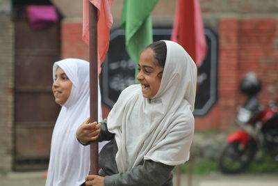 Close-up of smiling friends standing by flag