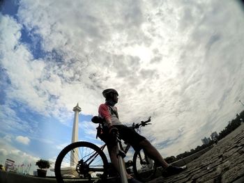 Low angle view of man riding bicycle against sky