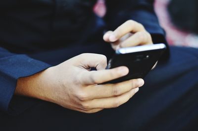 Midsection of man holding mobile phone