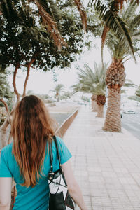 Rear view of woman standing on footpath