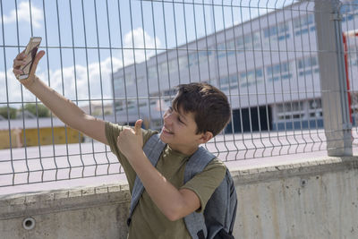 Teenage boy taking selfie by fence