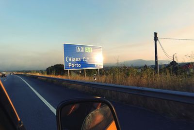 Road sign against sky during sunset