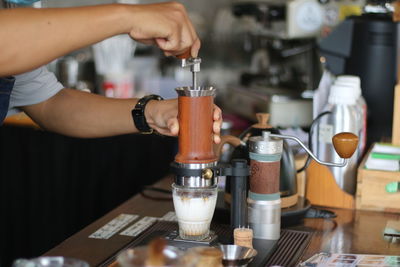 Cropped image of man pouring coffee in cafe